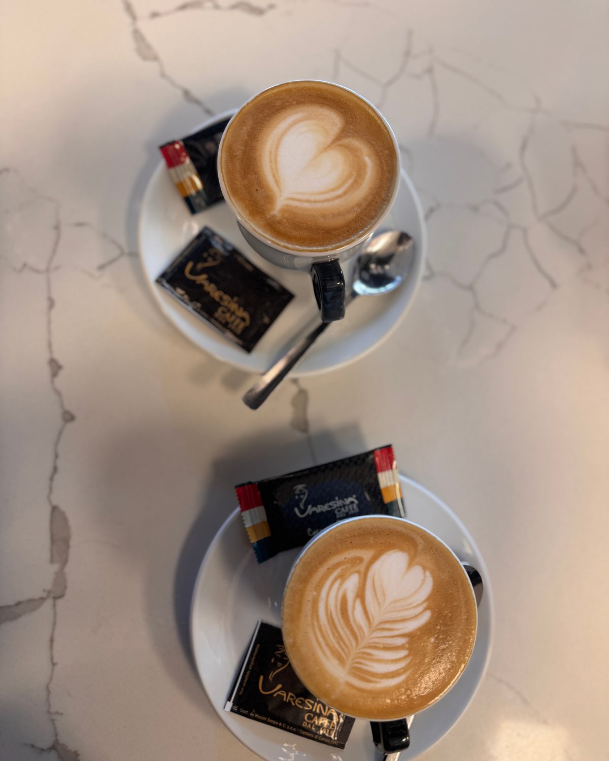 Zwei Cappuccino mit Latte Art und Gebäck von oben auf Marmor