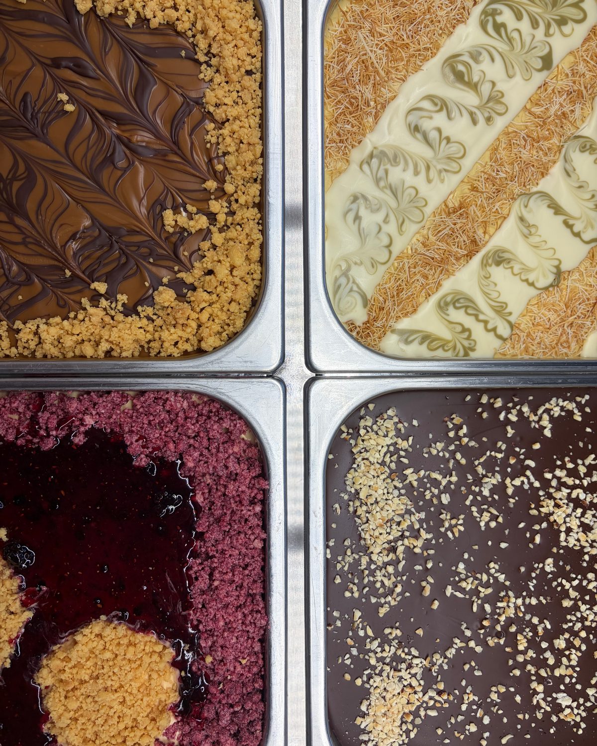 Vier frisch dekorierte Eiswannen von oben: Schokolade, Pistazie, Beere und Nuss