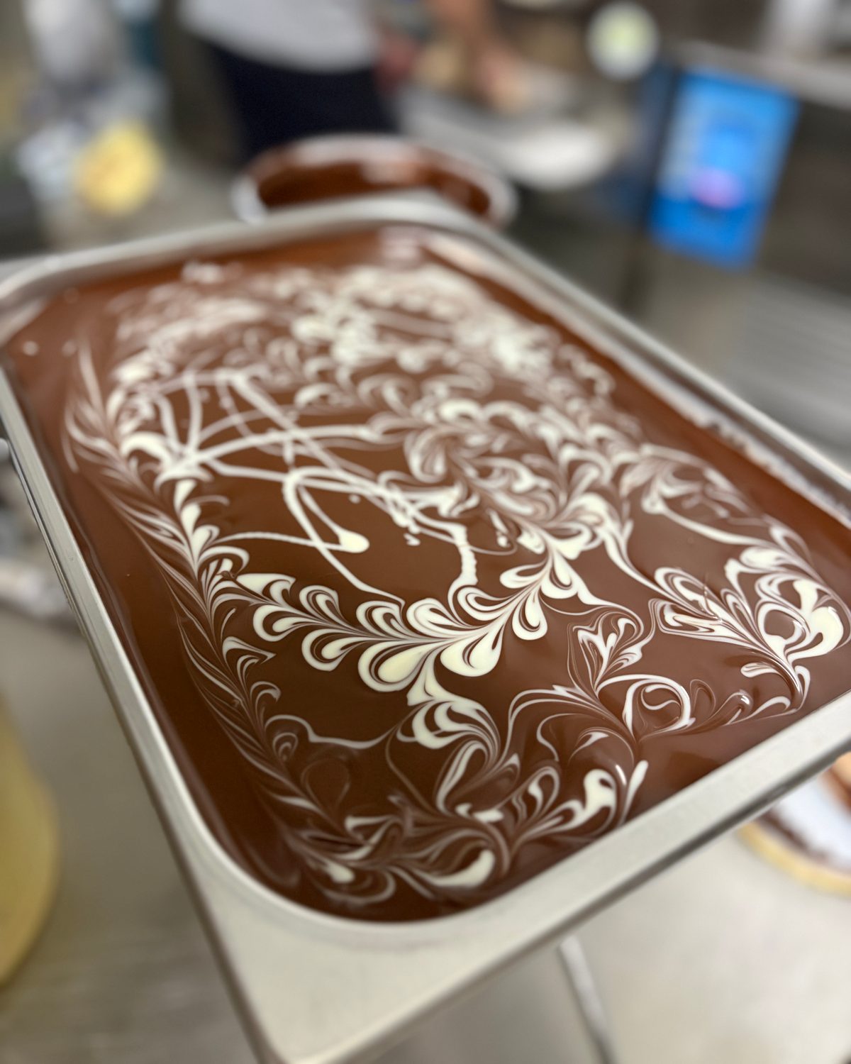 Frisch verzierte Schokoladen-Gelatowanne mit feinem weißem Rankenmuster