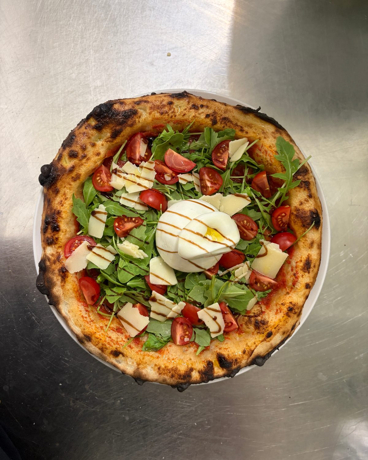 Pizza mit Burrata, Rucola, Kirschtomaten und Parmesan, von oben