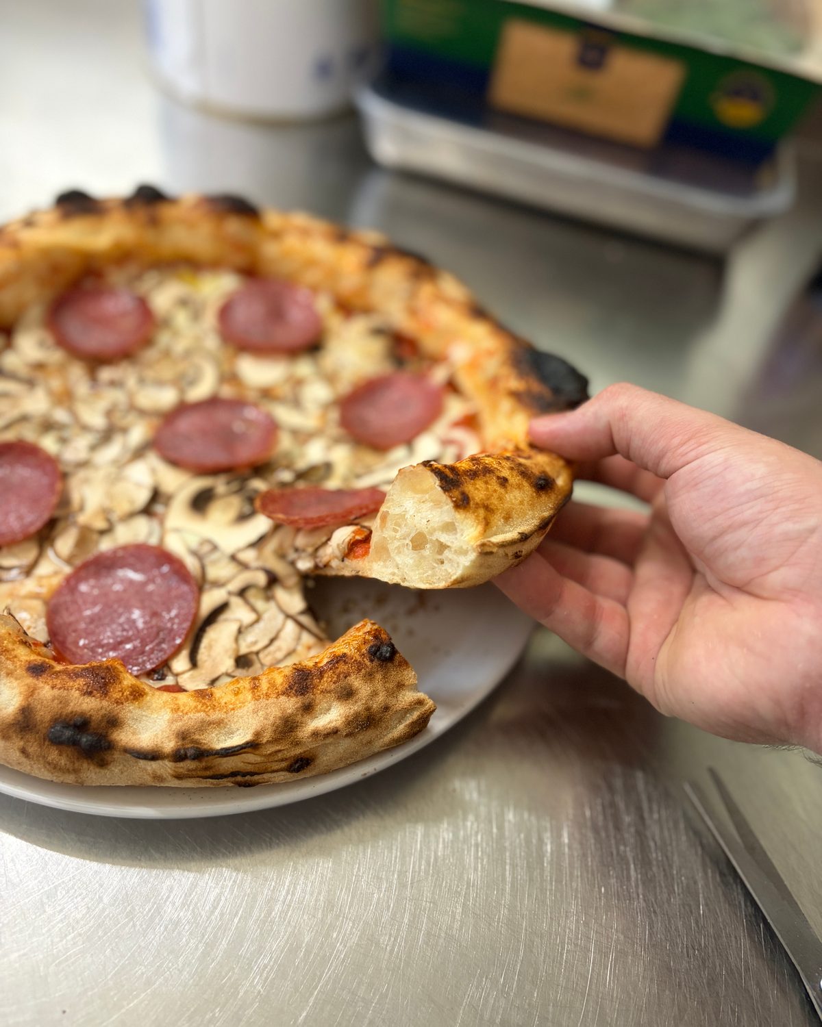Ein Stück Pizza Salami wird von der Pizza gehoben