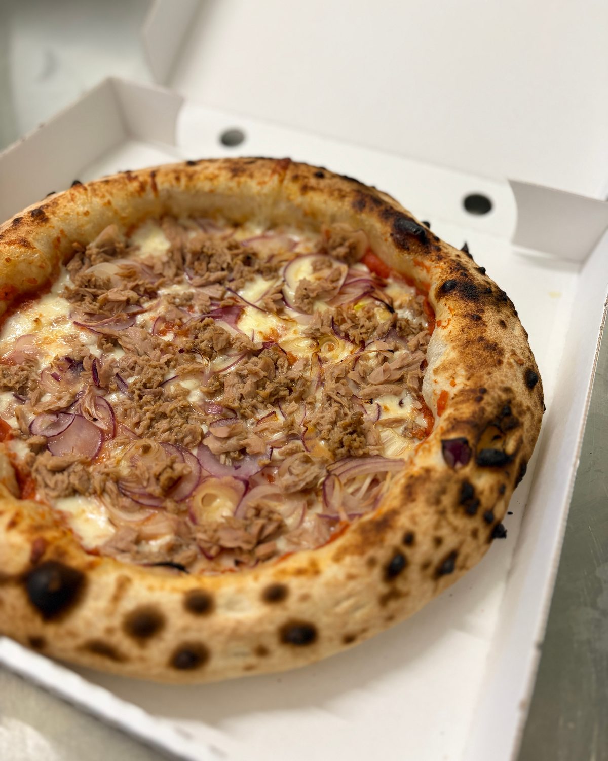 Pizza mit Thunfisch und Zwiebeln im Karton
