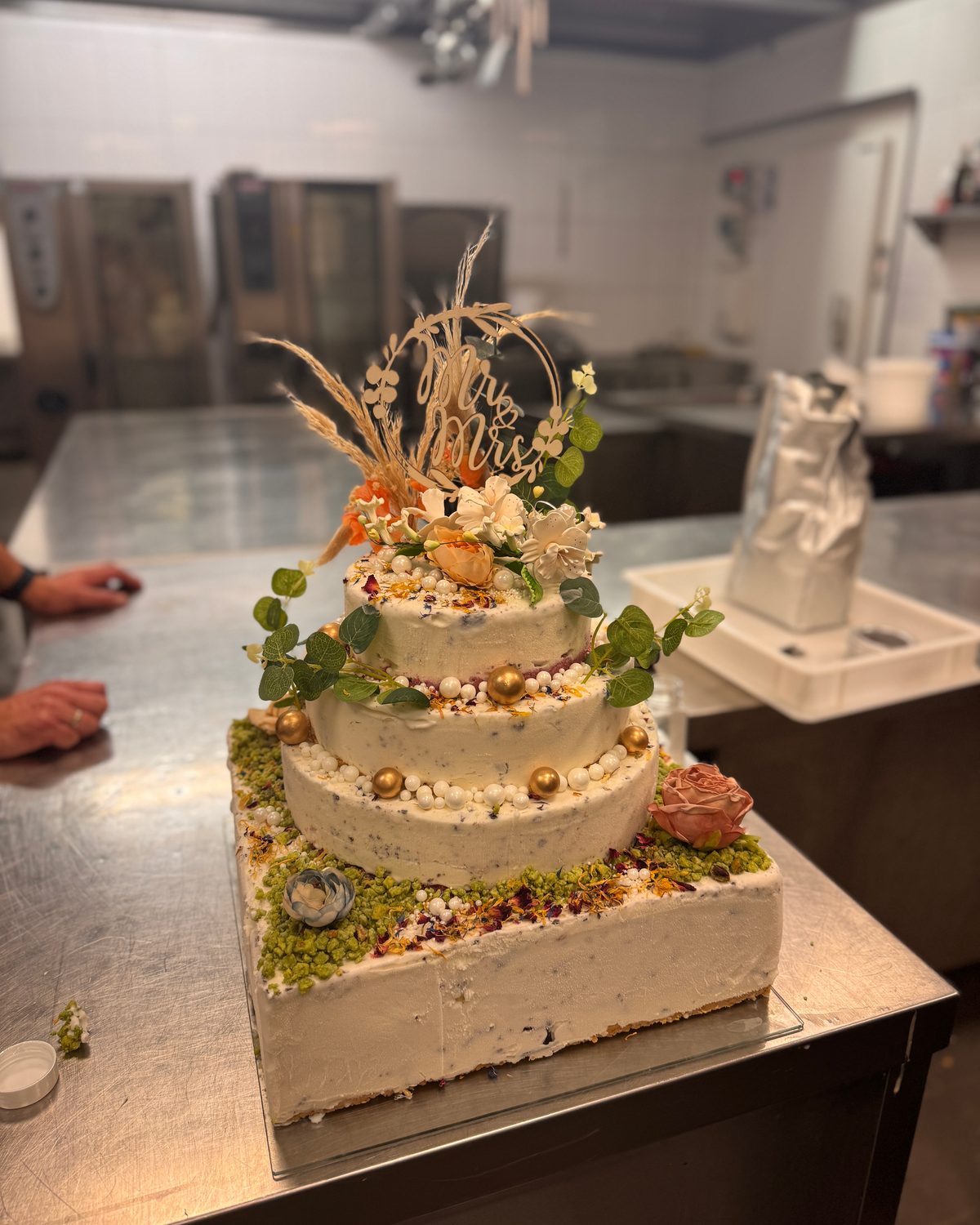 Dreistöckige Torte mit Trockenblumen auf der Arbeitsfläche der Backstube