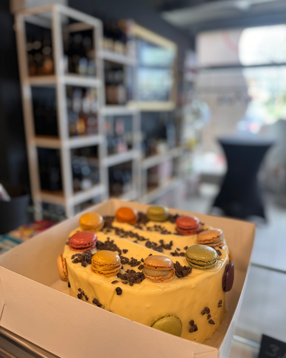 Torte mit bunten Macarons und Schokoladenstücken im Tortenkarton