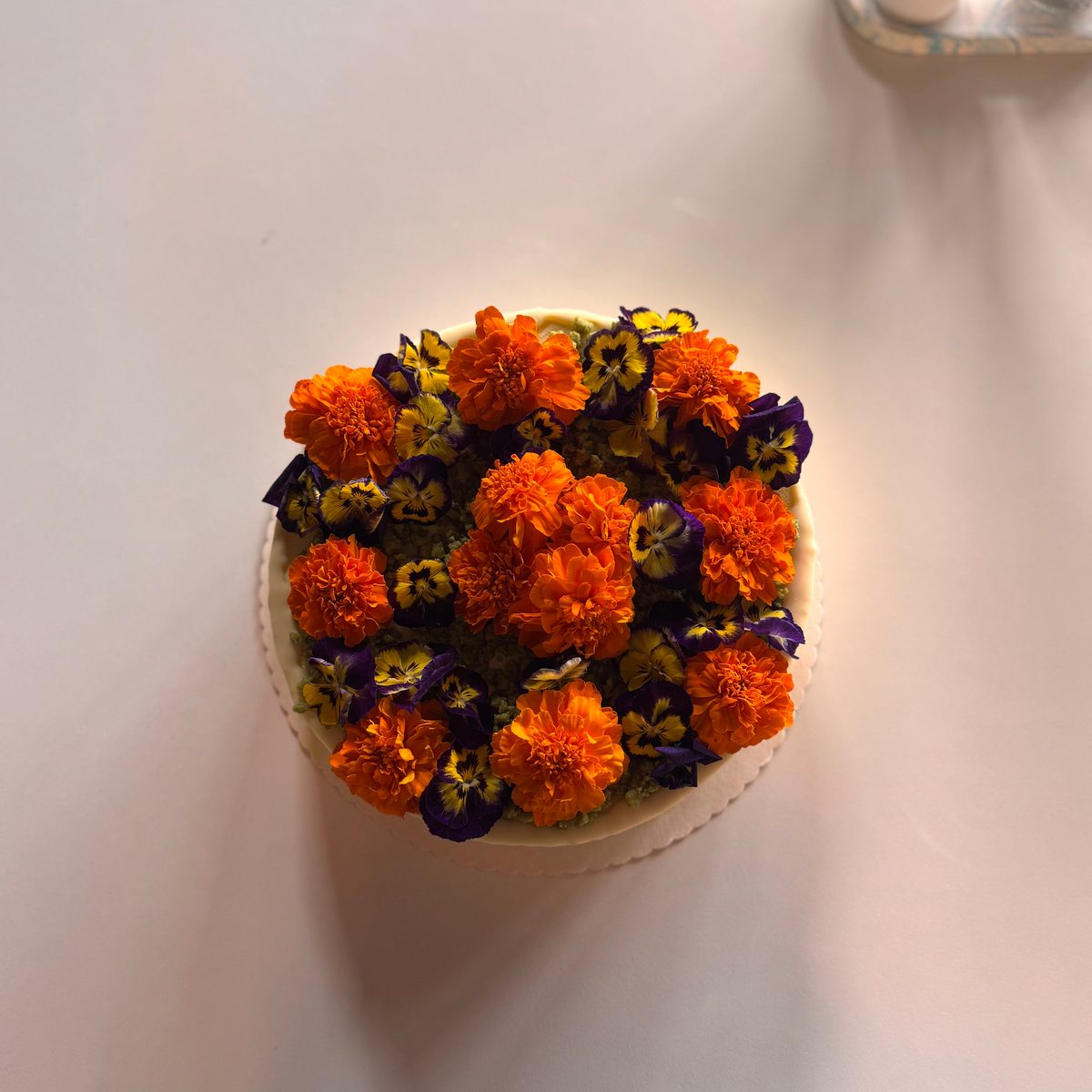 Torte von oben, ganz mit orangen und violetten Blüten belegt