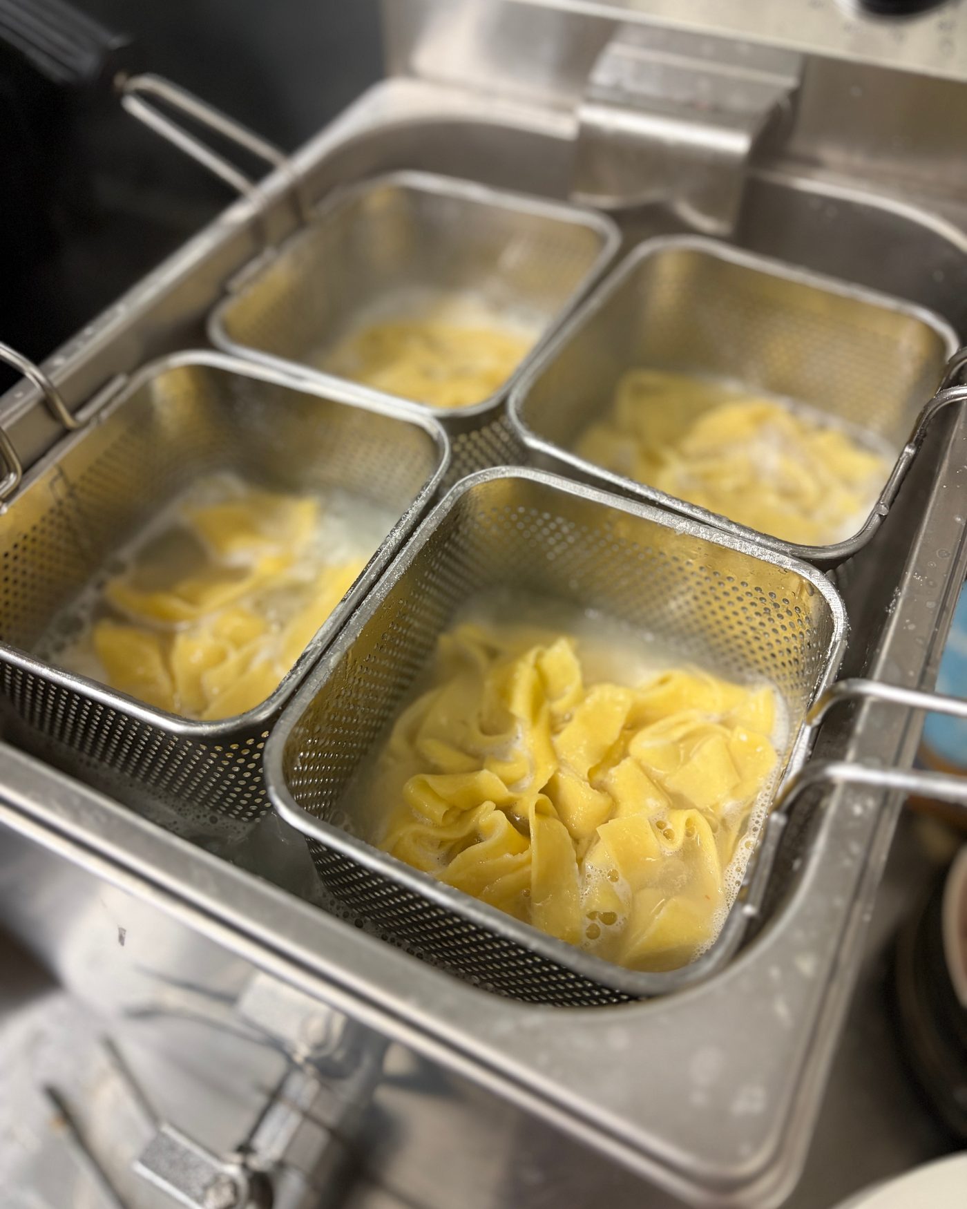 Frische gefüllte Pasta in vier Kochkörben in der Küche
