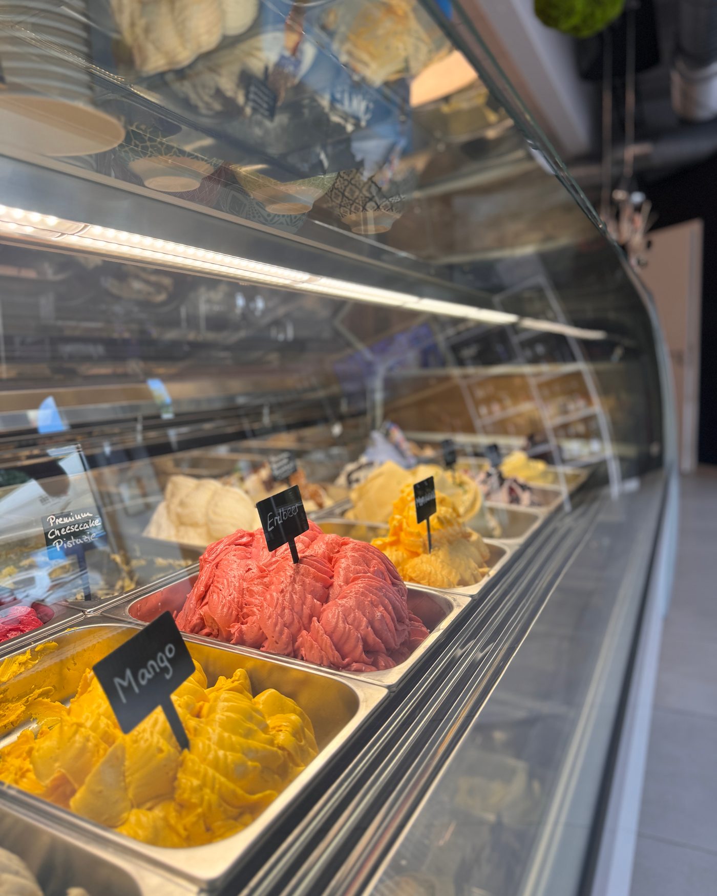 Gelato-Vitrine im Genuss Atelier mit bunten Eissorten und Sortenschildern
